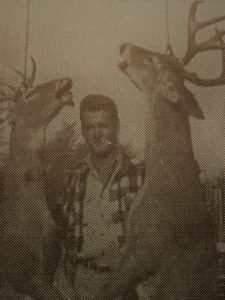 Myron standing by two hanging deer